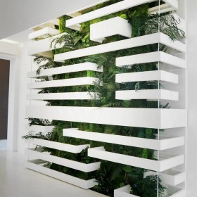 Mur végétal très dense installé sur mesure derrière une structure métallique et claustra d'architecte blanc.