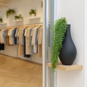 Mise en situation déco d'une chute de Callisia artificielle dans un vase noir sur une étagère en bois