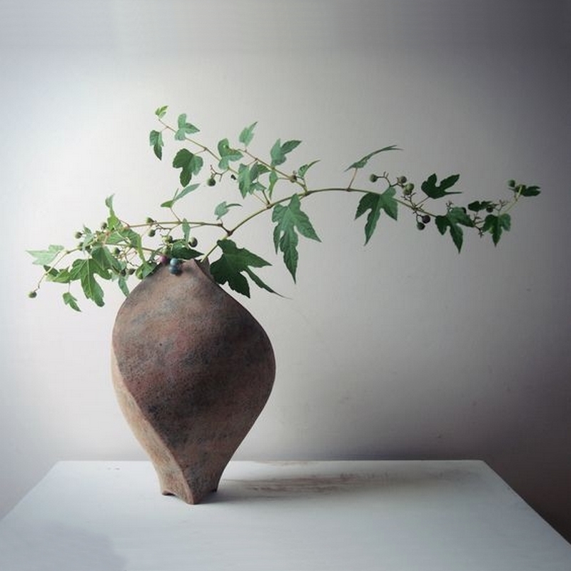 Vase en céramique sombre avec branches sur table blanche