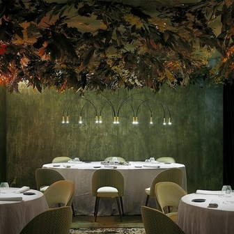 Salle de restaurant avec plafond végétal stabilisé sombre en fond, tables dressées