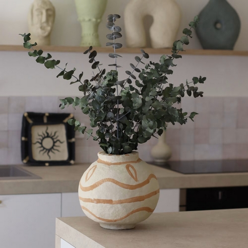 Petit pot avec feuillage stabilisé posé sur une table avec objets décoratifs