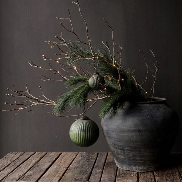 Vase sombre avec branches vertes de sapin et boules de noel, sol en bois